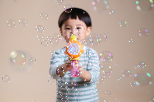 Child Blowing Bubbles, surrounded by iridescent spheres floating