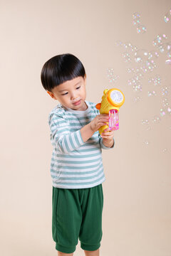 Adorable toddler shooting colorful soap bubbles