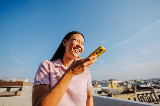 Woman laughing enjoying sunny day with smartphone