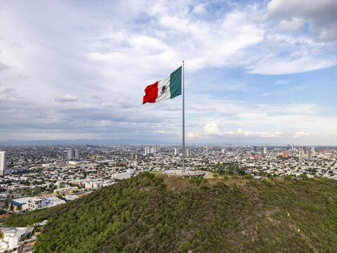Aerial view of the Mexican flag waving atop the Cerro del Obispado overlooking the urban landscape of Monterrey, Nuevo Leon, Mexico.