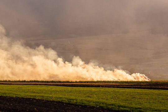 Burning Straw Stubble Producing Smoke and Air Pollution. Burning straw stubble in an agricultural field after harvest, producing thick smoke and air pollution during autumn field clearing.