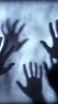 Dark, blurred silhouette of human hands and zombie palms on a white, foggy background in slow motion. Dark blue colors. Mysterious, creepy atmosphere, Halloween concept