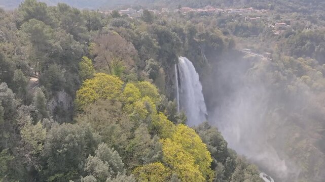 Aerial view of Marmore Falls surrounded by lush green forest and mist in Terni, Umbria, Italy.