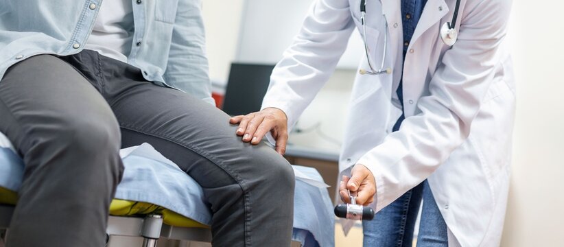 Doctor testing patient's knee reflex with hammer during neurological examination