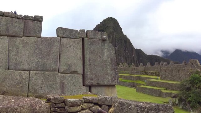 Massive Inca stone blocks at Machu Picchu, Peru, with Huayna Picchu mountain and ancient ruins in the background