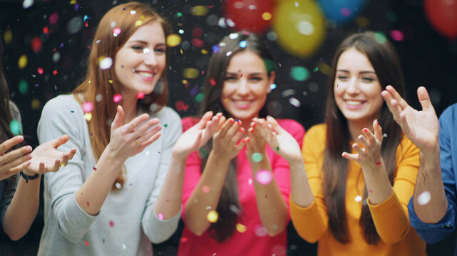 Birthday celebration with young women throwing colorful confetti in party setting with copy space