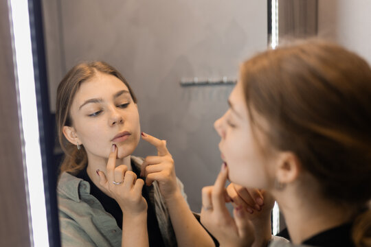 Teen girl looking at her lips in mirror, beauty and appearance concept