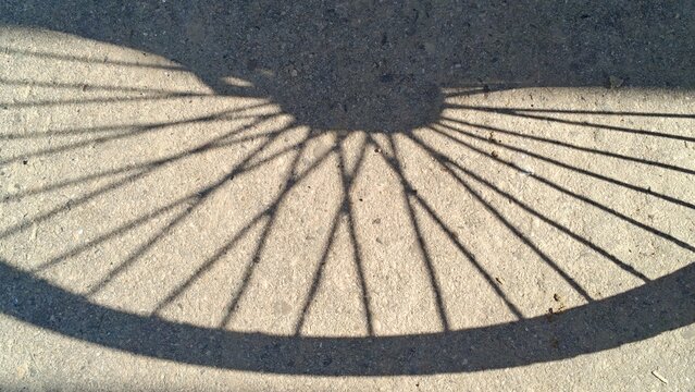 Bicycle wheel shadow cast on textured concrete ground with copy space