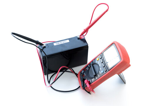 Multimeter measuring electrical voltage of battery on white background