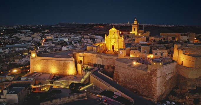 Aerial view of the illuminated Cittadella fortifications and cathedral at night in Victoria, Gozo, Malta.