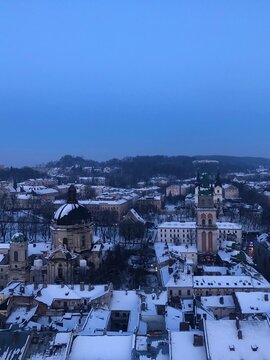 Winter panorama of Lviv old town with Dominican Cathedral at dusk. Beautiful high angle panoramic view of the historical center of Lviv, Ukraine, featuring snow-covered roofs and ancient church domes 