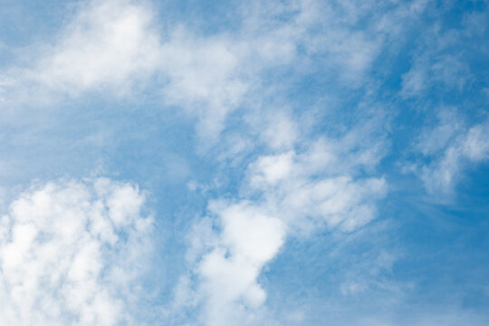 A soft blue sky scattered with fluffy white cumulus clouds and gentle cirrus veils. Pastel tones and even daylight create a serene and weightless mood for calm wellness backgrounds.