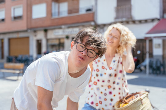 Curious teenage boy with Down syndrome looking around during sunny family walk in Spanish town