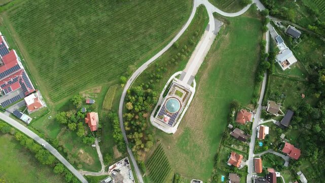 Top-down aerial view of Blessed Anton Martin Slomsek Church surrounded by vineyards, roads and green countryside in Kosaki, Maribor, Slovenia.
