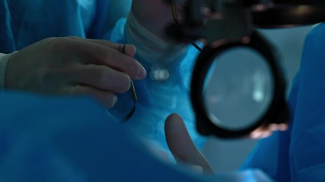 Eye microsurgery in low light, surgeon in sterile gown holding fine instruments near patient eye with microscope lens, moody blue atmosphere