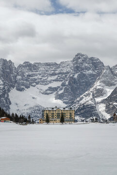 View of a snow covered lake surrounded by mountains in the Dolomites, Italy. Winter tourism attracts visitors to this area.