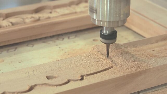 Automated CNC woodworking and shaping of wood components. CNC machine cutting wooden parts in a furniture factory.  Woodworking and wooden furniture manufacturing at a furniture factory.