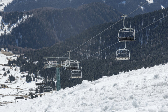 Ski lifts operate in the Dolomites as people enjoy winter sports in the snowy mountains of Italy. Alpine scenery attracts many visitors.
