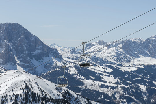 Ski lifts carry skiers over snow-covered mountains in the Dolomites, Italy. Winter sports are popular at this ski resort.