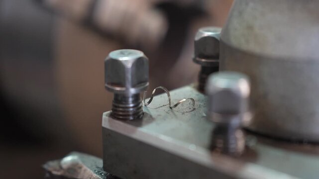 The metalworking process by turning machine. Industrial lathe machine cutting metal creating swarf in a mechanical workshop, the metal shavings are clearly visible during the turning process 
