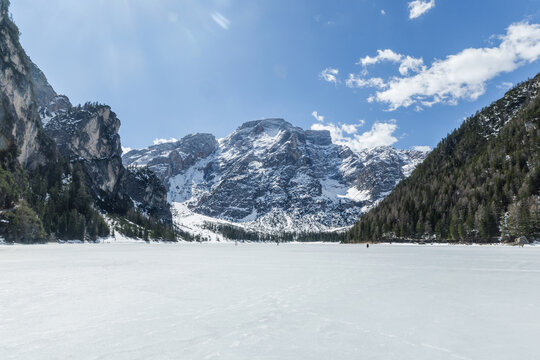 Alpine lake surrounded by snow covered mountains in the Dolomites during winter season with visitors enjoying the scenery.