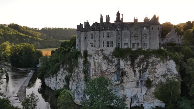 Majestic view of Walzin castle perched on a rocky cliff during a golden sunset