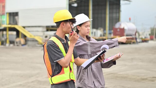 Two workers inspect shipping containers at a port