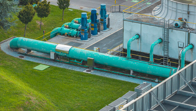 Aerial view of industrial water cooling and pumping system with large turquoise pipelines, electric pumps and cooling infrastructure at a manufacturing plant in Brescia, Lombardy, Italy.