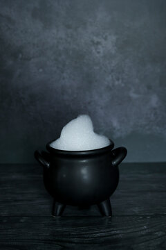 Witches cauldron filled with soap and bubbles on dark spooky backdrop with room for copy space