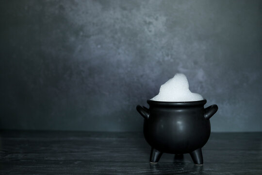Witches cauldron filled with soap and bubbles on dark spooky backdrop with room for copy space