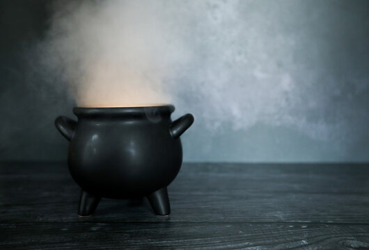 Smokey glowing cauldron on dark spooky backdrop with copy space, perfect for Halloween flyer