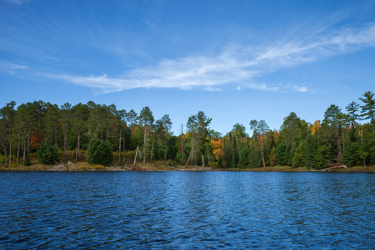 Beautiful blue lake in northern Minnesota with pines and trees in autumn color on the shore on a sunny afternoon