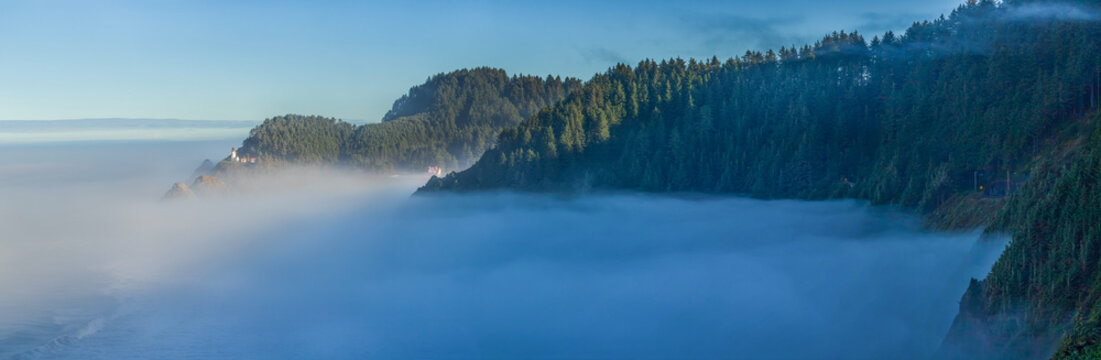 Beautiful wide panoramic view of a historic lighthouse on a misty rocky ocean coast at sunrise