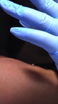 Vertical close-up shot of a doctor in blue gloves spinning a blue multi-tool pen. Medical examination and healthcare concept
