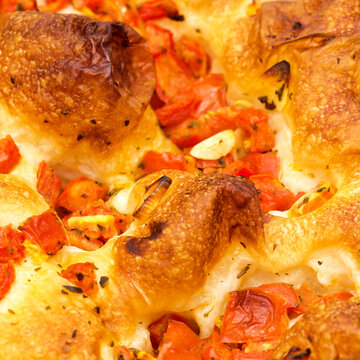 Freshly baked Italian focaccia bread with tomatoes in an aluminum tray isolated on white background

