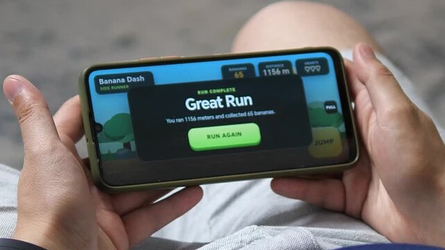 Person holds a smartphone after completing a colorful running game, highlighting casual mobile gaming, gamified entertainment and everyday digital leisure.