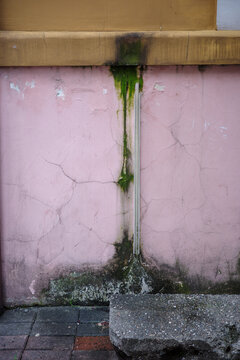 Algae streak, damp staining and cracked wall around conduit, moisture runoff causing facade deterioration, leakage and exterior repair problem