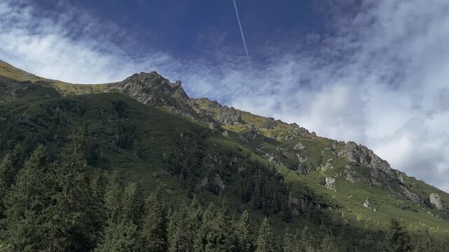 High mountain peaks with green alpine slopes and dense coniferous forest under blue sky with cirrus clouds. Wilderness landscape. Poland tatras 