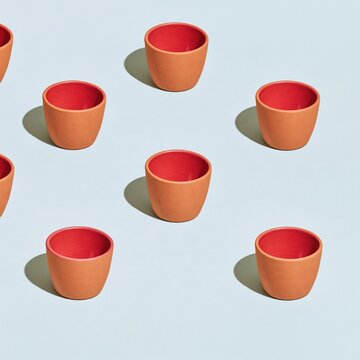 Red earthen clay tea cups arranged in a pattern on a lilac background, featuring vivid colors for bengali festival and pandal design