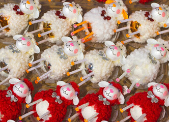 Top view of handmade sheep ornaments with fluffy wool textures in red and white, arranged in neat rows as a festive decorative background © ravital