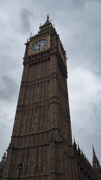 Close up vertical view of Big Ben clock tower in London under cloudy overcast sky, famous British landmark