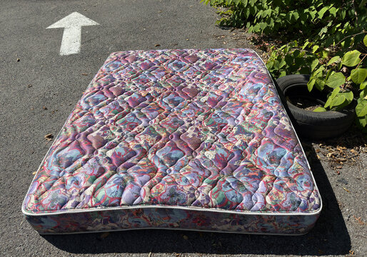 Matelas install&eacute; dans la rue. Meubles abandonn&eacute;s en bord de route lors d'un d&eacute;m&eacute;nagement et poubelles.