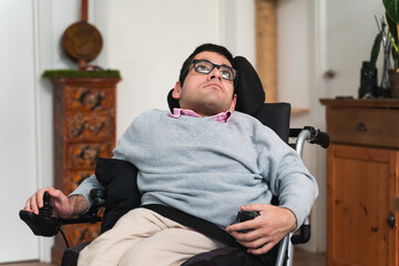Young man in a power wheelchair looking up thoughtfully at home © Lorenzo Capunata