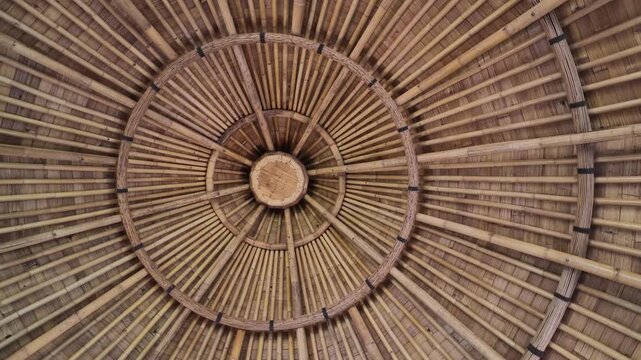 Rotating low angle view of traditional bamboo gazebo roof structure inside Bali resort