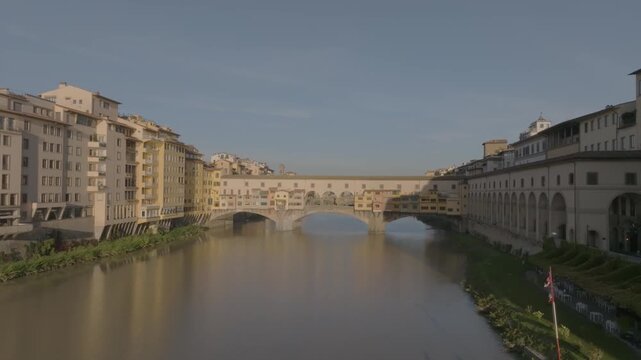 Aerial view of the historic Ponte Vecchio bridge spanning the Arno river with rowing boats on the water in Florence, Tuscany, Italy.