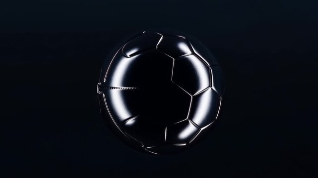 Slow motion tracking shot of glossy black soccer ball spinning and rotating against dark isolated studio background