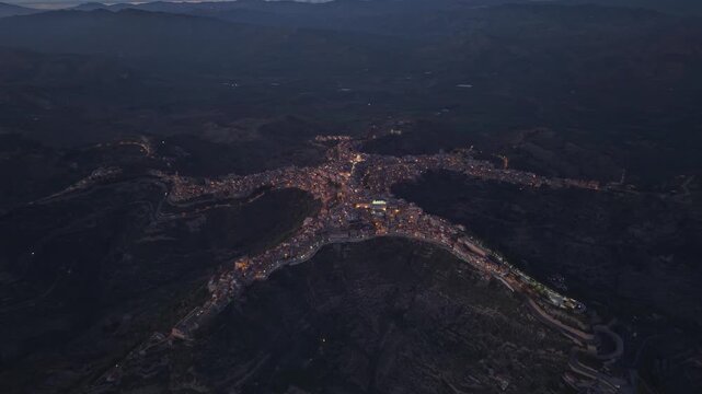 Aerial view of the town of Centuripe illuminated at night, showcasing its unique star-shaped layout across the hills of Centuripe, Sicily, Italy.