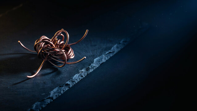 Tangled copper wire knot on dark slate with copy space representing complexity and regulation, concept