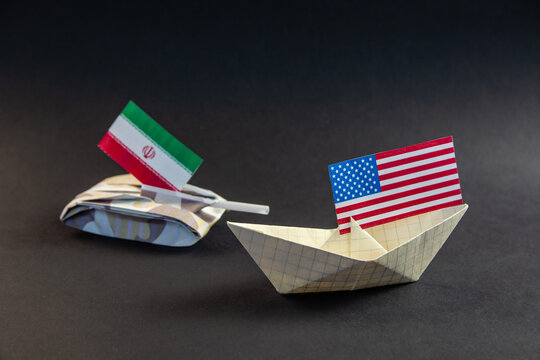 USA Iran conflict concept with paper tank and boat. Geopolitical crisis, Strait of Hormuz blockade and military tension between United States and Iranian national flags