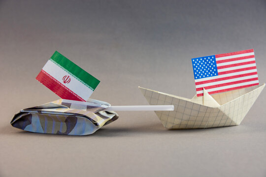 USA Iran conflict concept with paper tank and boat. Geopolitical crisis, Strait of Hormuz blockade and military tension between United States and Iranian national flags
